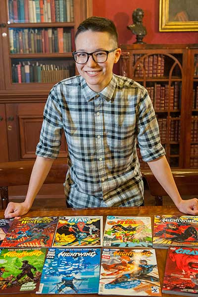 student thea cheuk stands at a table with several comic books on display